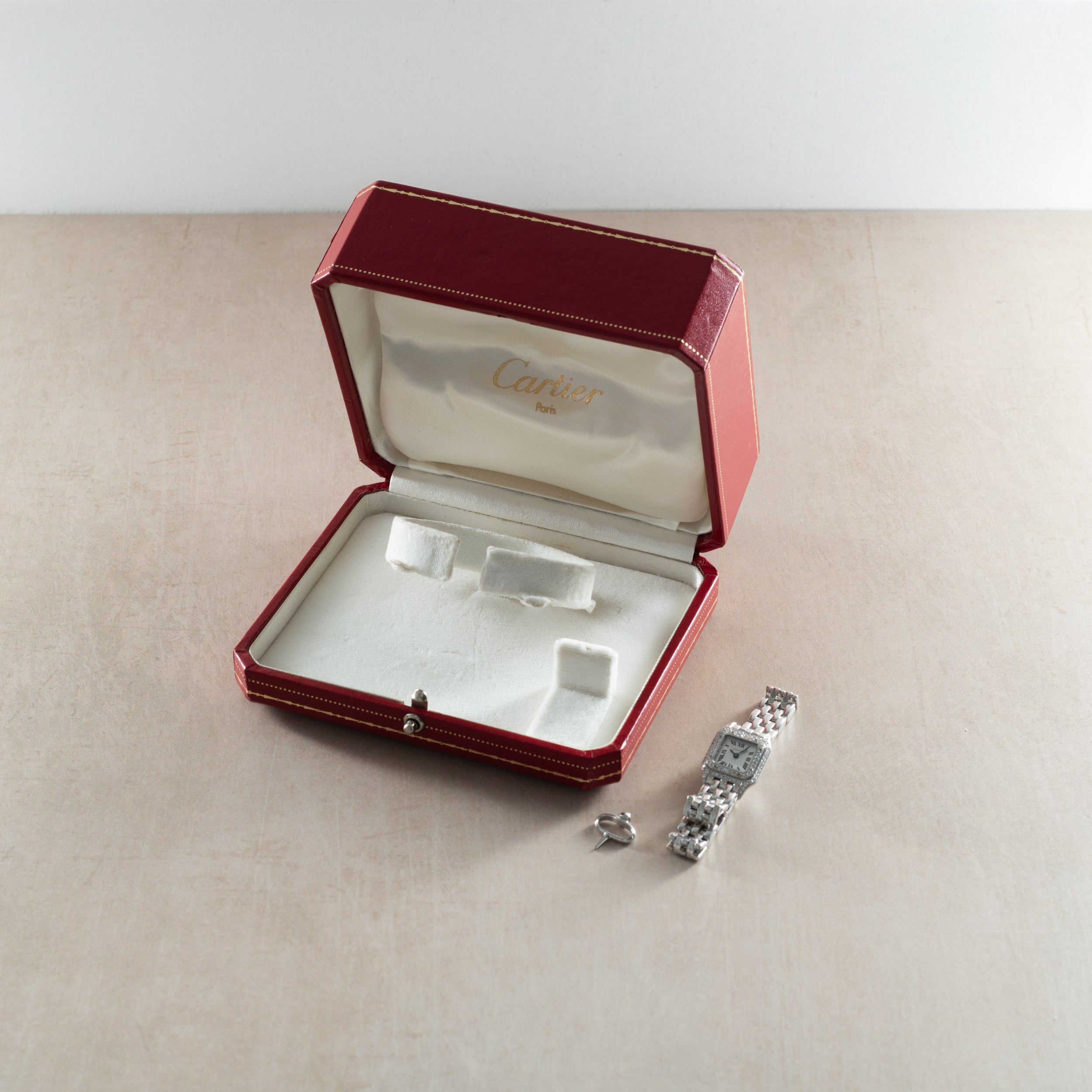 Cartier Panthere diamond watch with matching ring displayed in open burgundy leather box.