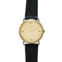 Hermès watch with cream dial, gold-tone case, gold hands, and black textured leather strap.