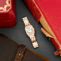 Rose gold and white rectangular watch with diamond bezel and linked bracelet on dark surface with red box and leather accesso