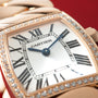 Rose gold square watch with diamond bezel, white dial, Roman numerals, and blue hands against red background.
