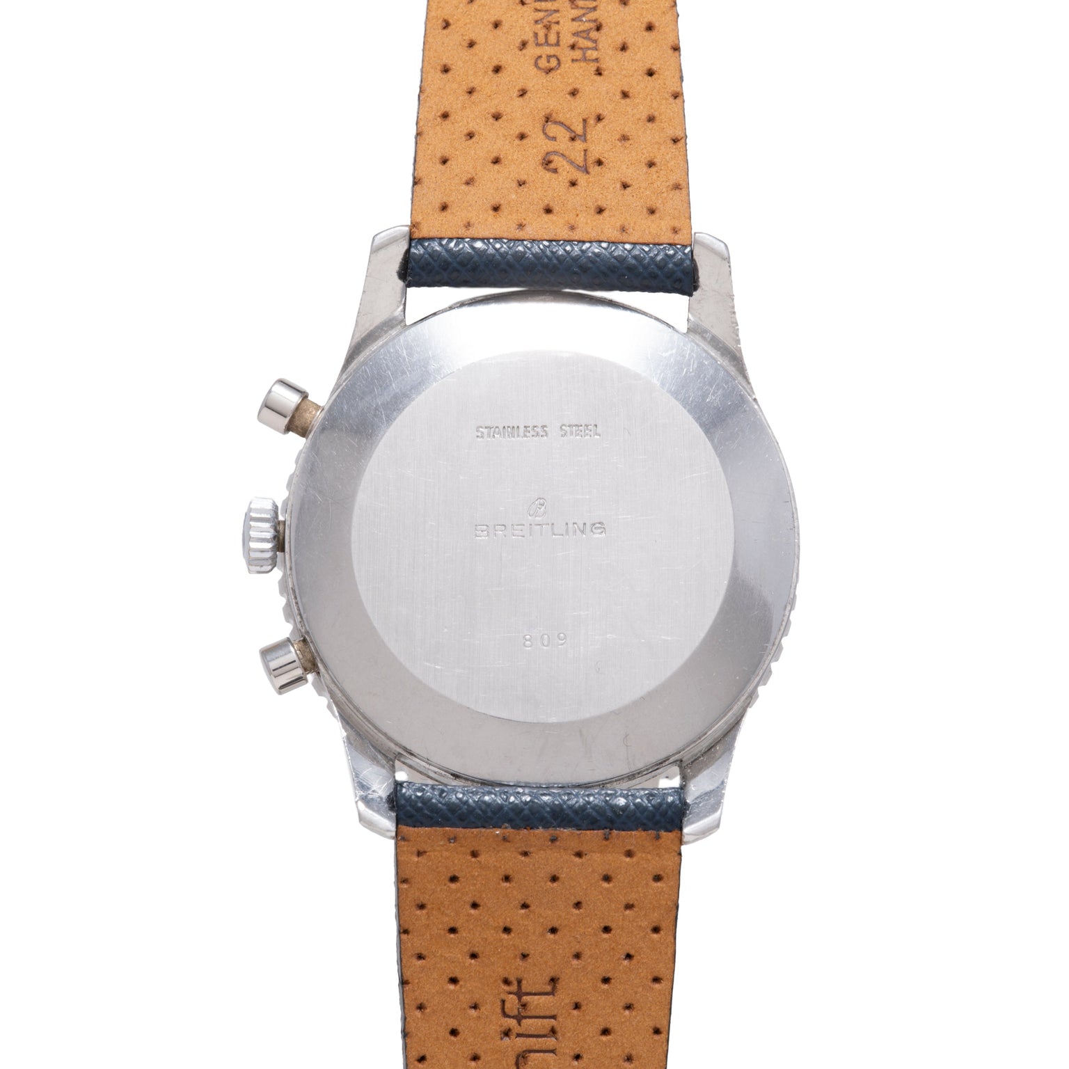 Stainless steel watch back showing Breitling branding and markings with tan perforated leather strap with dark blue trim.