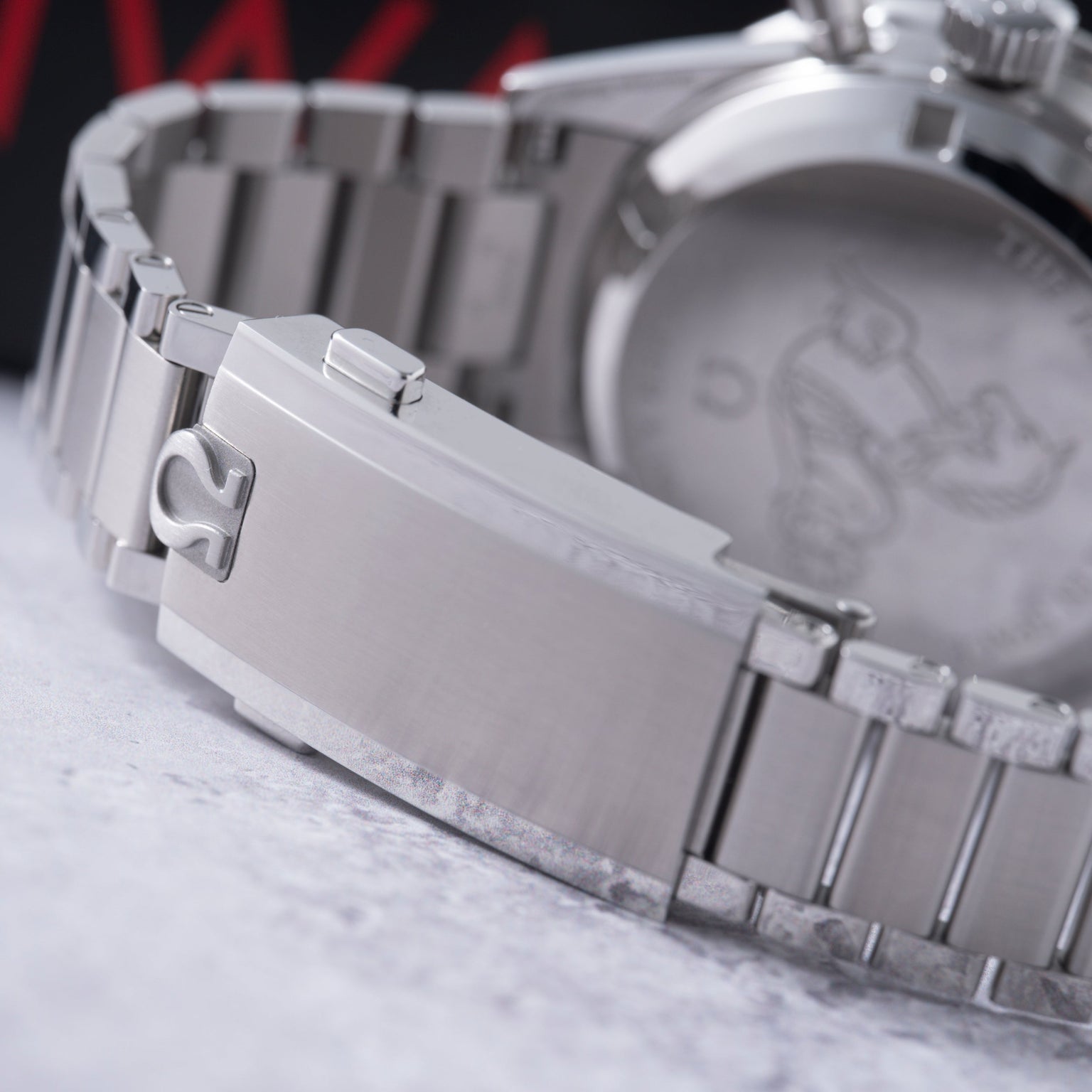 Stainless steel chronograph watch with rectangular case and bracelet, shown at angle displaying side profile and dial.