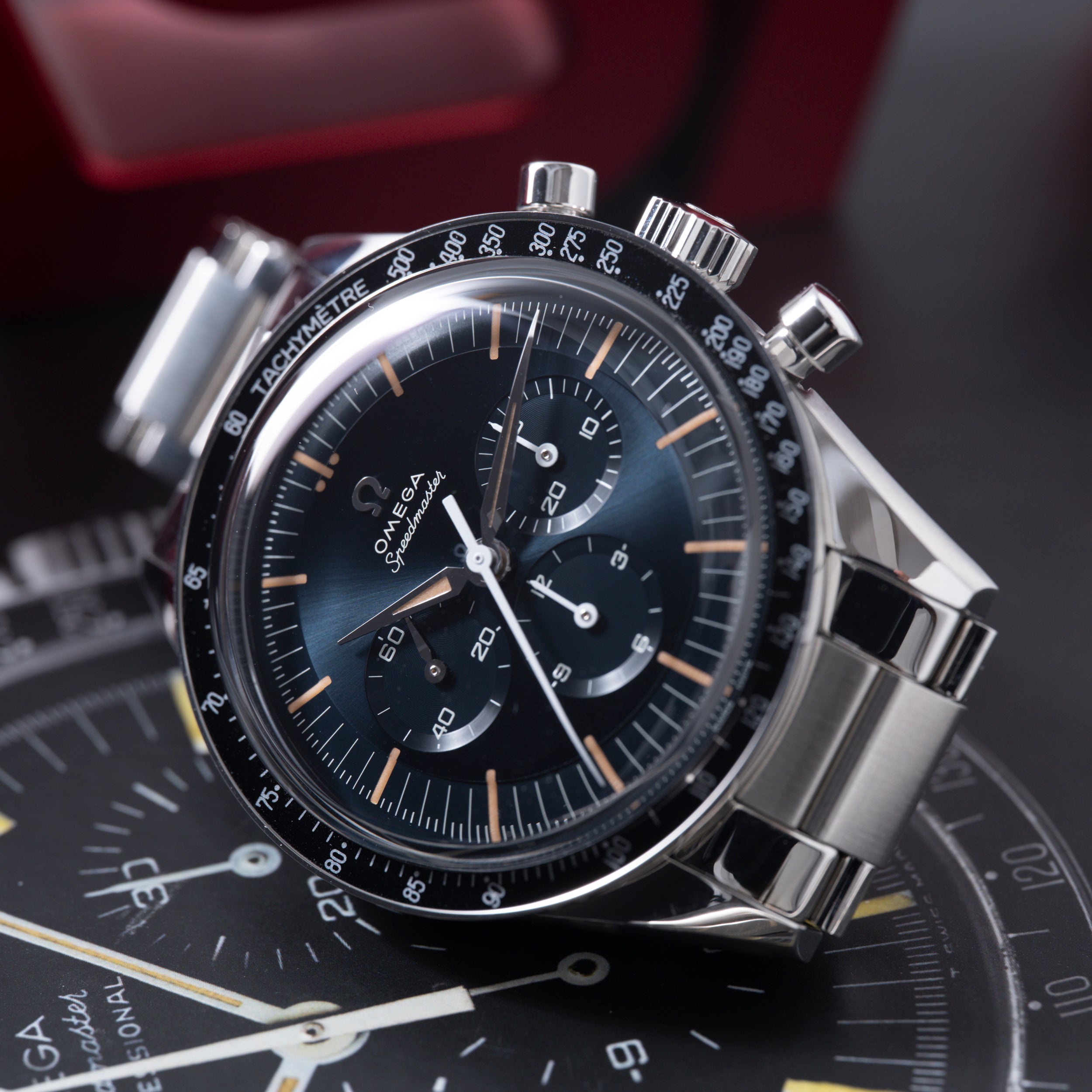 Stainless steel chronograph watch with black dial, tachymeter bezel, three subdials, and orange hour markers.