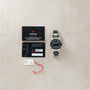 Tudor Pelagos Ultra dive watch with black dial, steel bracelet, warranty booklet, and certification card displayed.