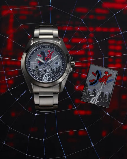 A silver-toned Spider-Man wristwatch with a detailed Spider-Man graphic dial, displayed next to a Spider-Man themed card on a dark background with a web pattern and red glowing city lights.