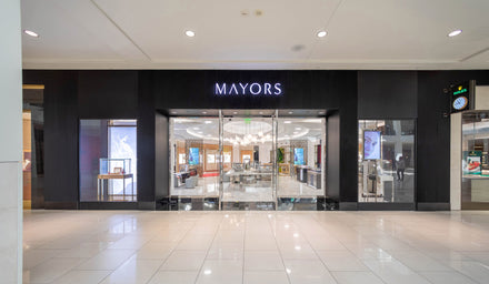 Front view of a MAYORS jewelry store in a shopping mall with glass doors and displays inside.