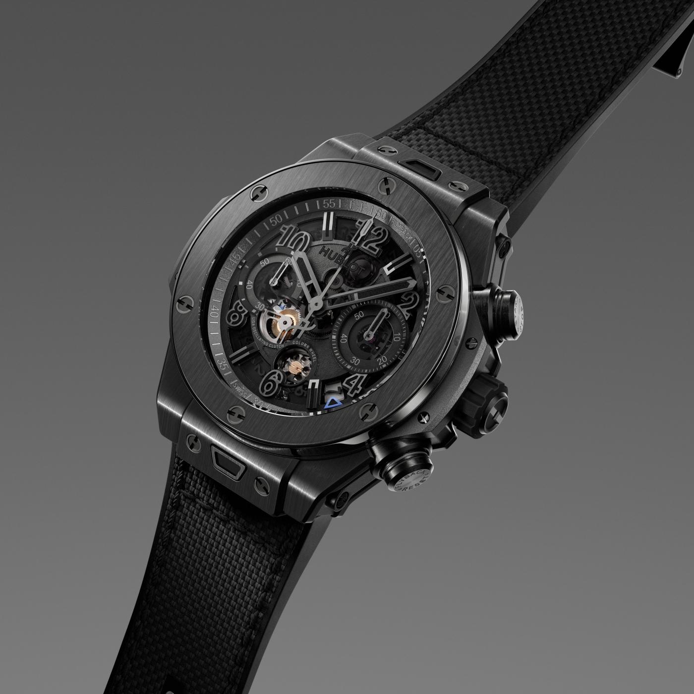All-black chronograph watch with skeleton dial showing exposed movement, textured rubber strap, and side pusher buttons.