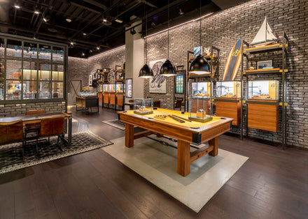 Modern store interior with display cases, pool table, nautical decor, and framed photos on brick walls.