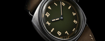 A close-up of a vintage-style wristwatch with a green dial and tan leather strap on a black background.