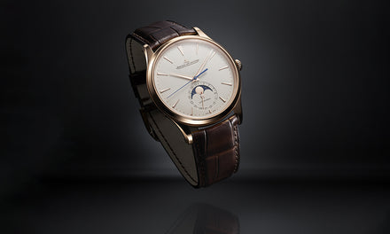 A luxury wristwatch with a brown leather strap and a moon phase display on a dark background.