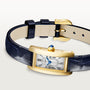 The Cartier Tank Américaine features a luxurious gold rectangular case, white dial with black Roman numerals, blue hands, and a dark blue leather strap—a true timeless classic.