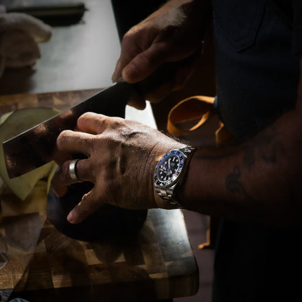 Person cutting fruit with a Rolex GMT Master II on their wrist