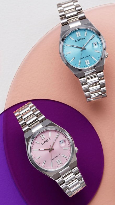 Two Citizen watches with different colored faces on a gradient background
