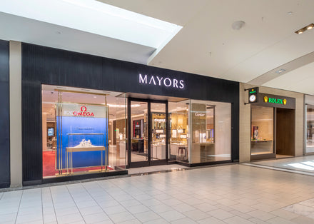 Storefronts of Mayors jewelry and Rolex in a shopping mall with glass displays and branded signs.