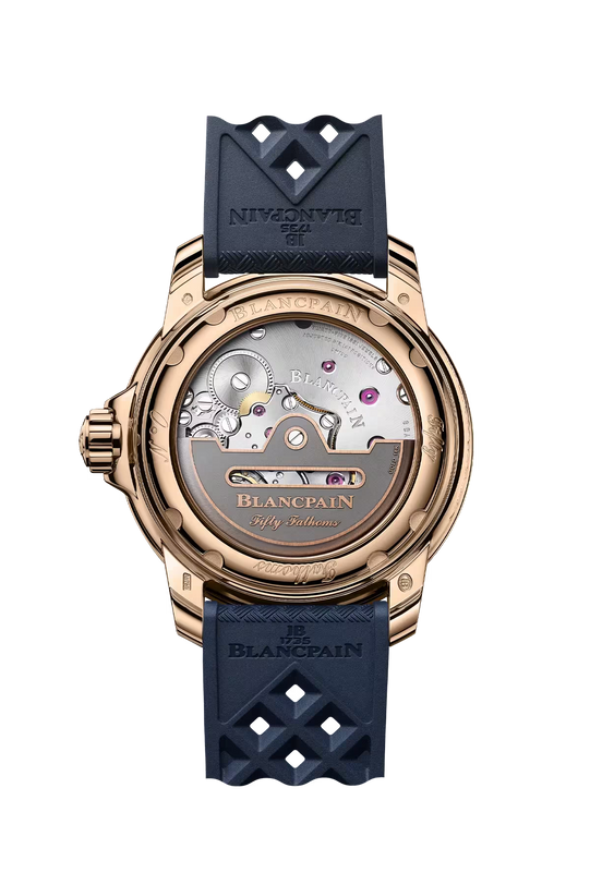 Rose gold watch with sunburst blue dial, visible mechanical movement on caseback, dark blue rubber strap with diamond cutout 