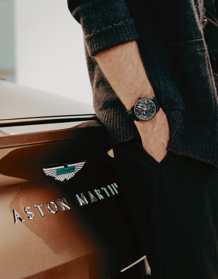 Girard-Perregaux watch on a model standing beside an Aston Martin car