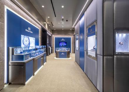 A modern Grand Seiko watch boutique with glass display cases and blue accent walls.