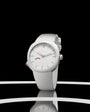 White round watch with white fabric band, silver hour markers, and small red accent on dial.
