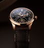 Luxury watch with black leather strap and rose gold case on a dark background