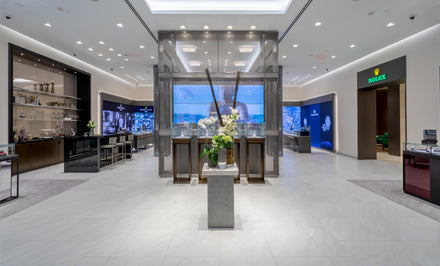Luxury watch and jewelry store interior with display cases, bright lighting, and a Rolex section on the right.