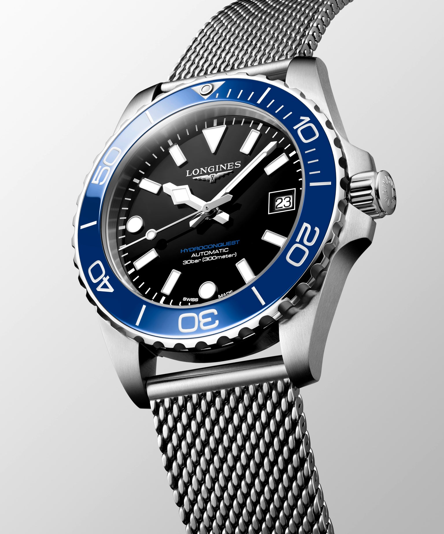 Longines watch with blue bezel and silver mesh band on a light gray background