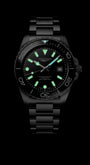 Black wristwatch with glowing green face on a black background