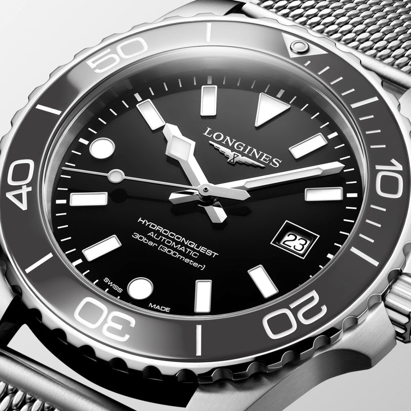 Longines watch with black dial and silver metal bracelet on a light gray background