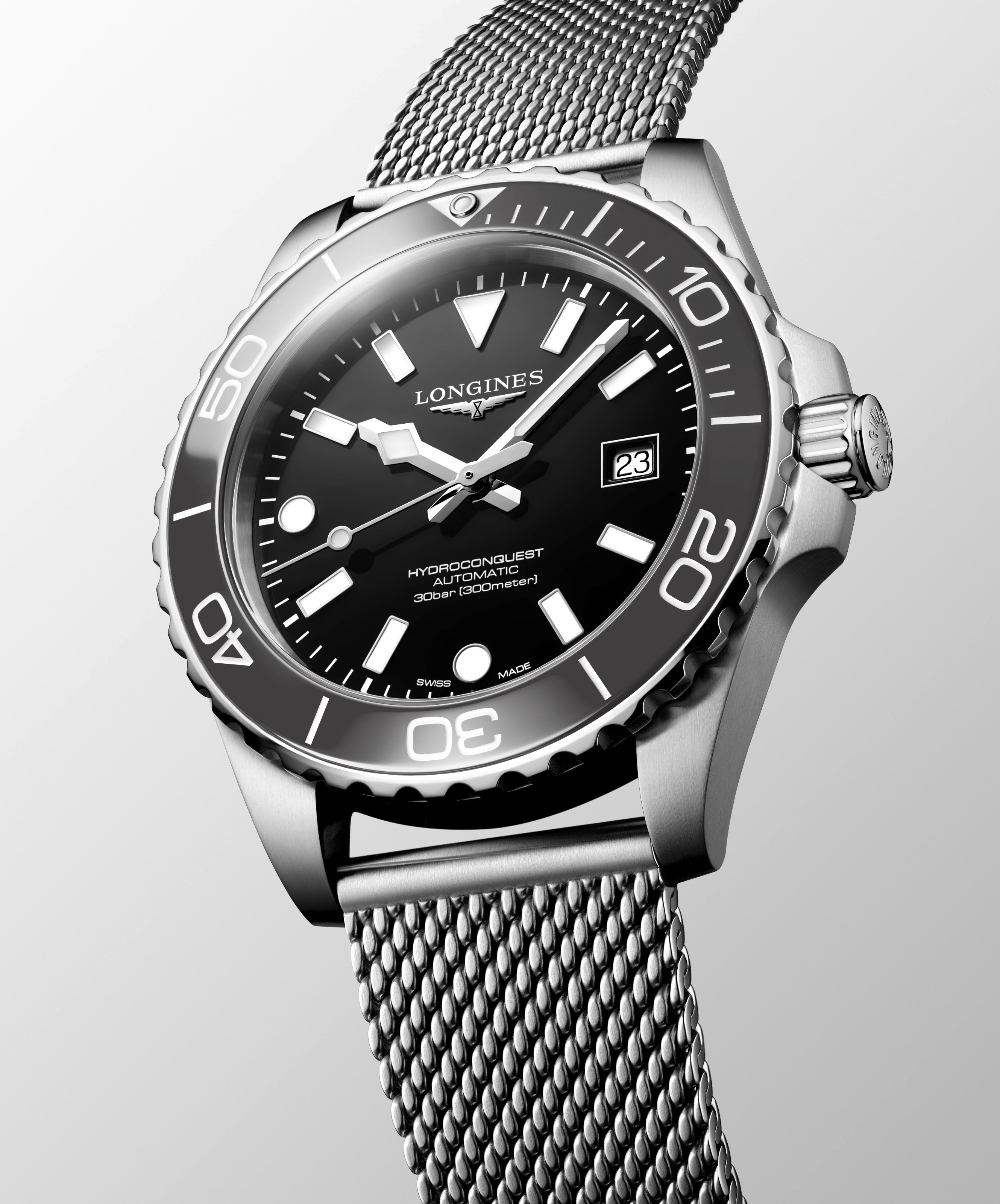 Longines watch with black dial and silver mesh band on a light gray background