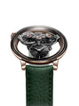 The MB&F SP One Rose Gold wristwatch features visible gears, a black face, and a green leather strap, shown on a white background.