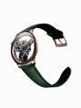 The MB&F SP One Rose Gold is a luxury wristwatch featuring a green leather strap and visible mechanical gears, showcased on a white background.