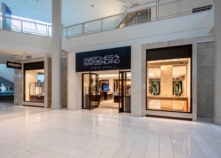 Exterior of Watches of Switzerland store in a mall, with glass doors and display windows.