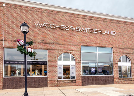 A brick storefront with large windows and a sign reading Watches of Switzerland.