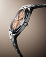 Two-tone stainless steel watch with salmon dial, applied indices, and matching bracelet displayed at an angle.