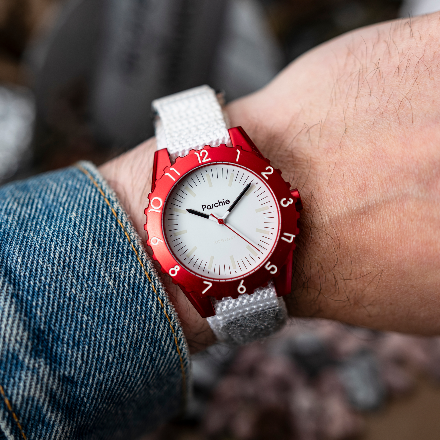 A person wearing a Parchie Lunar-Time Limited Editions for Hodinkee 36 wristwatch with a white dial and silver strap on their left wrist.