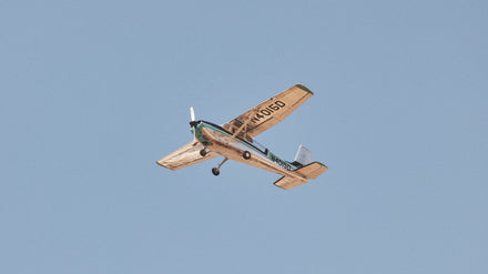 A small single-engine airplane flying in a clear blue sky.