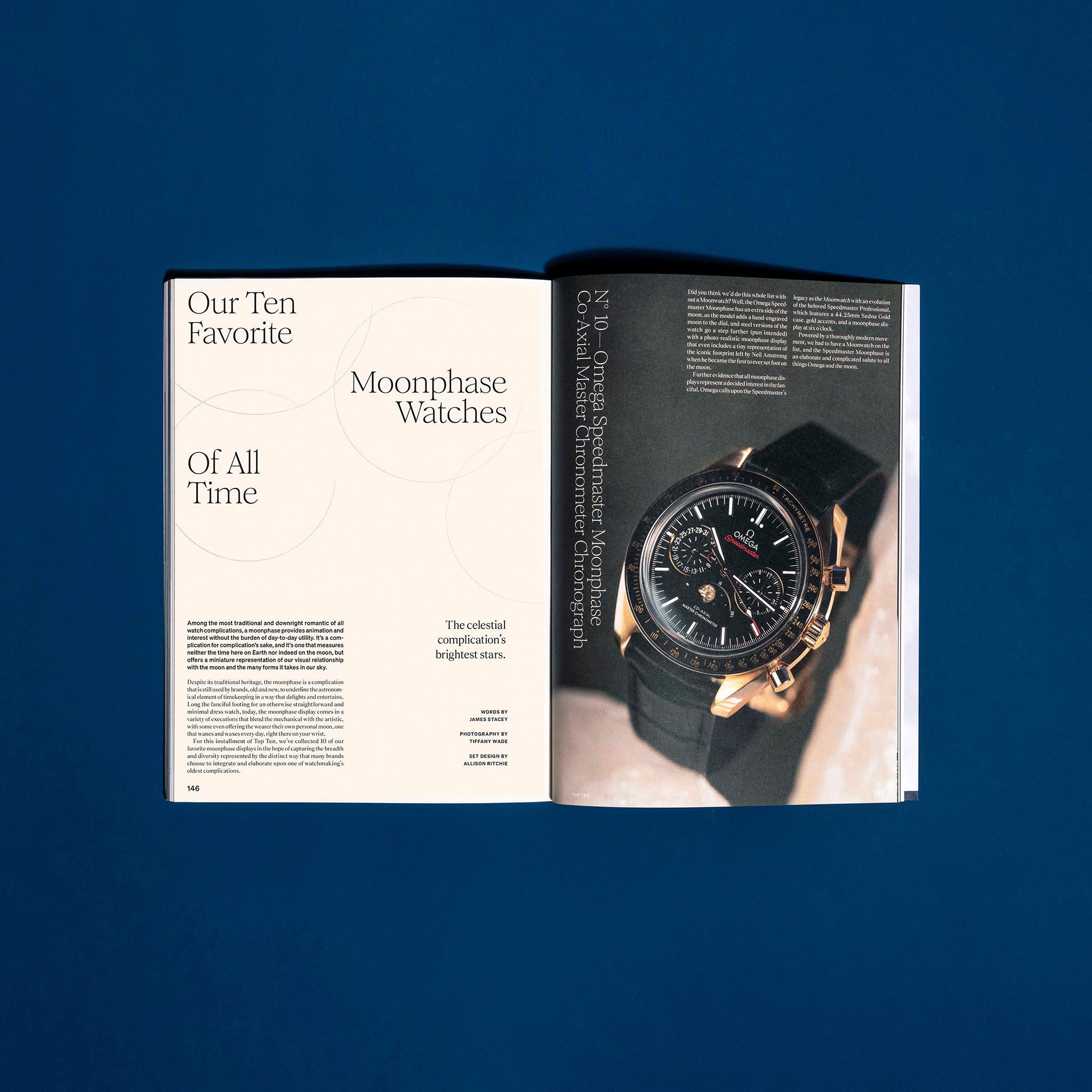 An open HODINKEE Magazine, Volume 12 by Hodinkee sits on a blue surface, showing the article Our Ten Favorite Moonphase Watches of All Time, with a large wristwatch photo and references to classic watch ads.
