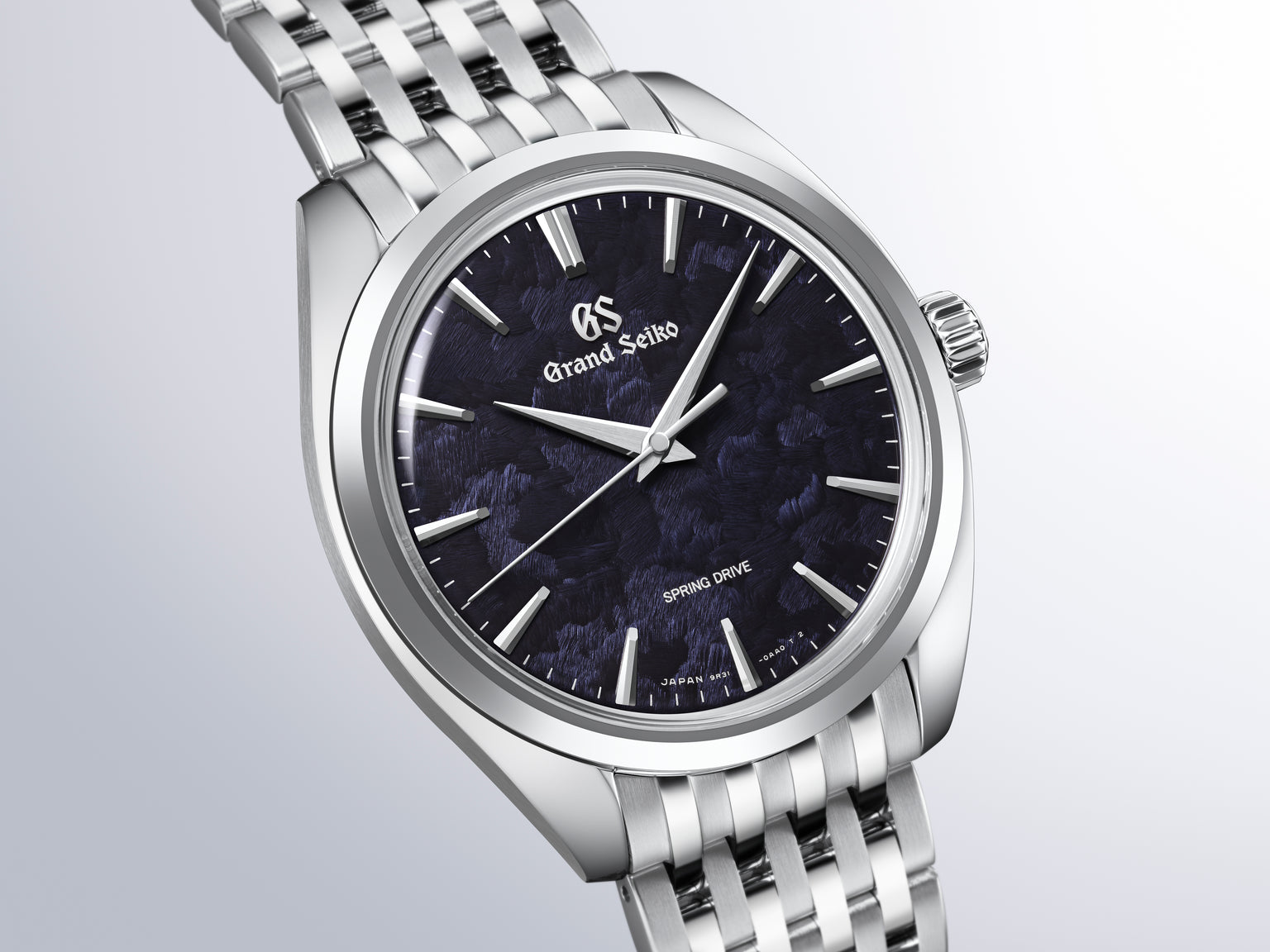 Grand Seiko watch with silver stainless steel bracelet, dark blue dial, and applied hour markers.