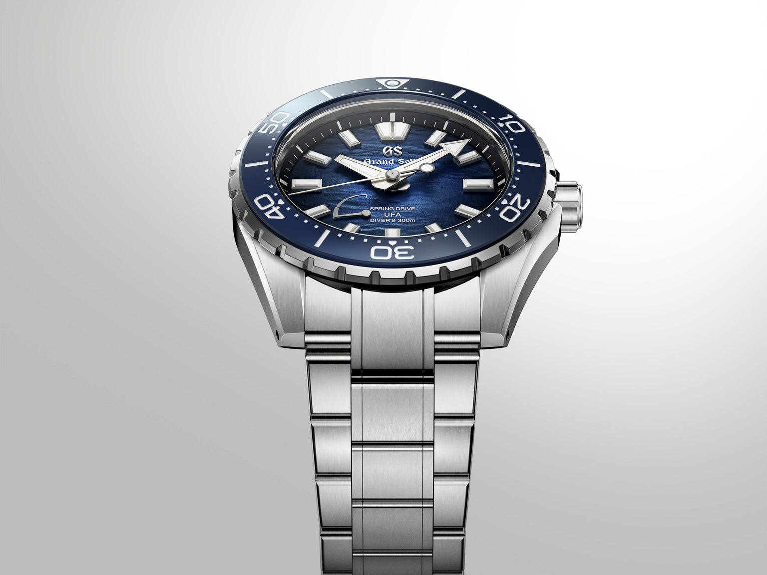 Stainless steel dive watch with dark blue dial, white hour markers, and matching blue rotating bezel on metal bracelet.