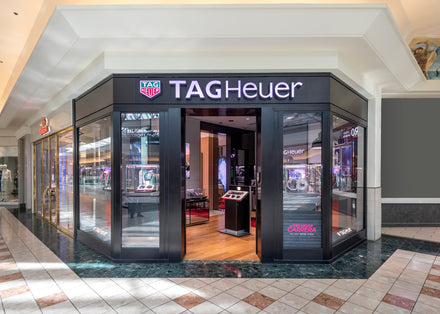 A TAG Heuer store with glass walls and watches displayed inside at a shopping mall.