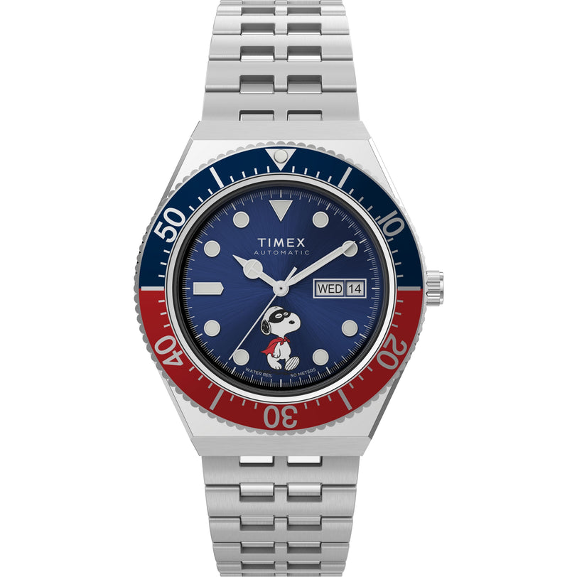 The Timex M79 Automatic x Peanuts watch features a blue and red bezel, blue dial with day-date display, and Snoopy in sunglasses and red shorts on the face, finished with a silver stainless-steel bracelet.
