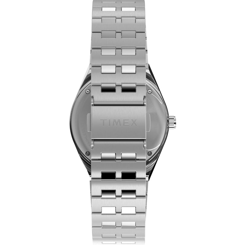 A close-up of the back of a Timex G SS QZ PEANUTS GMT 38 SLVR DL SS BLT 25 wristwatch shows its stainless-steel case, metal link bracelet, and an engraved Timex logo. The watch crown appears on the right side.