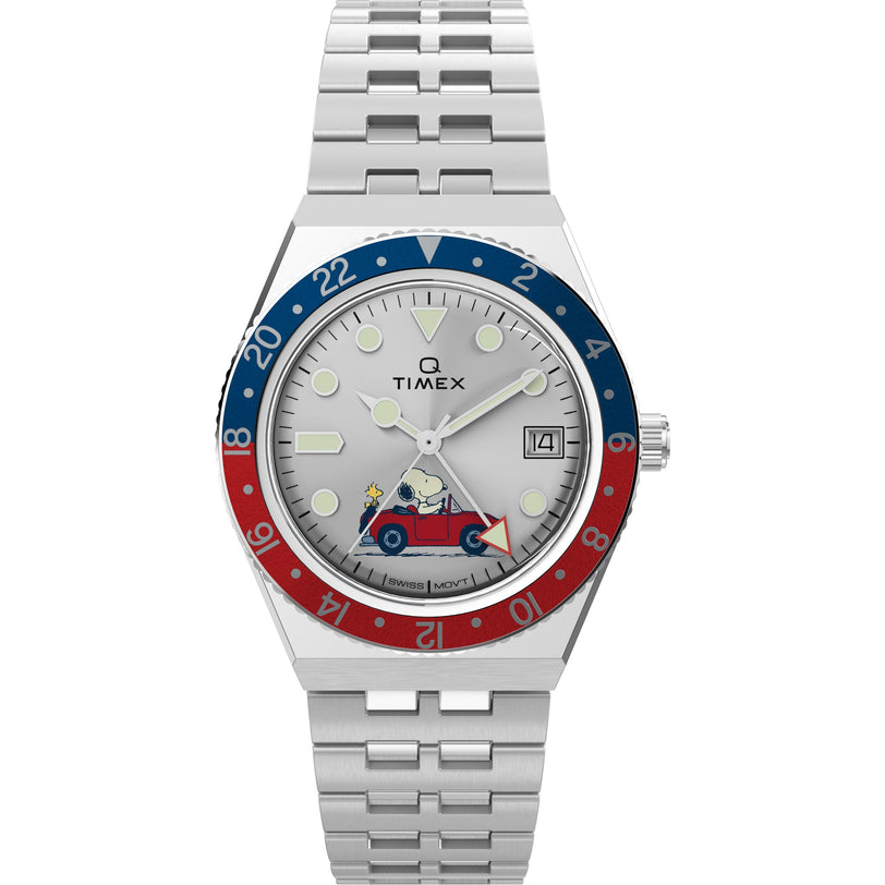 The Timex G SS QZ PEANUTS GMT 38 SLVR DL SS BLT 25 features a stainless-steel case, red and blue bezel, white dial with date display, and Snoopy driving a red car illustrated on the lower half of the face.