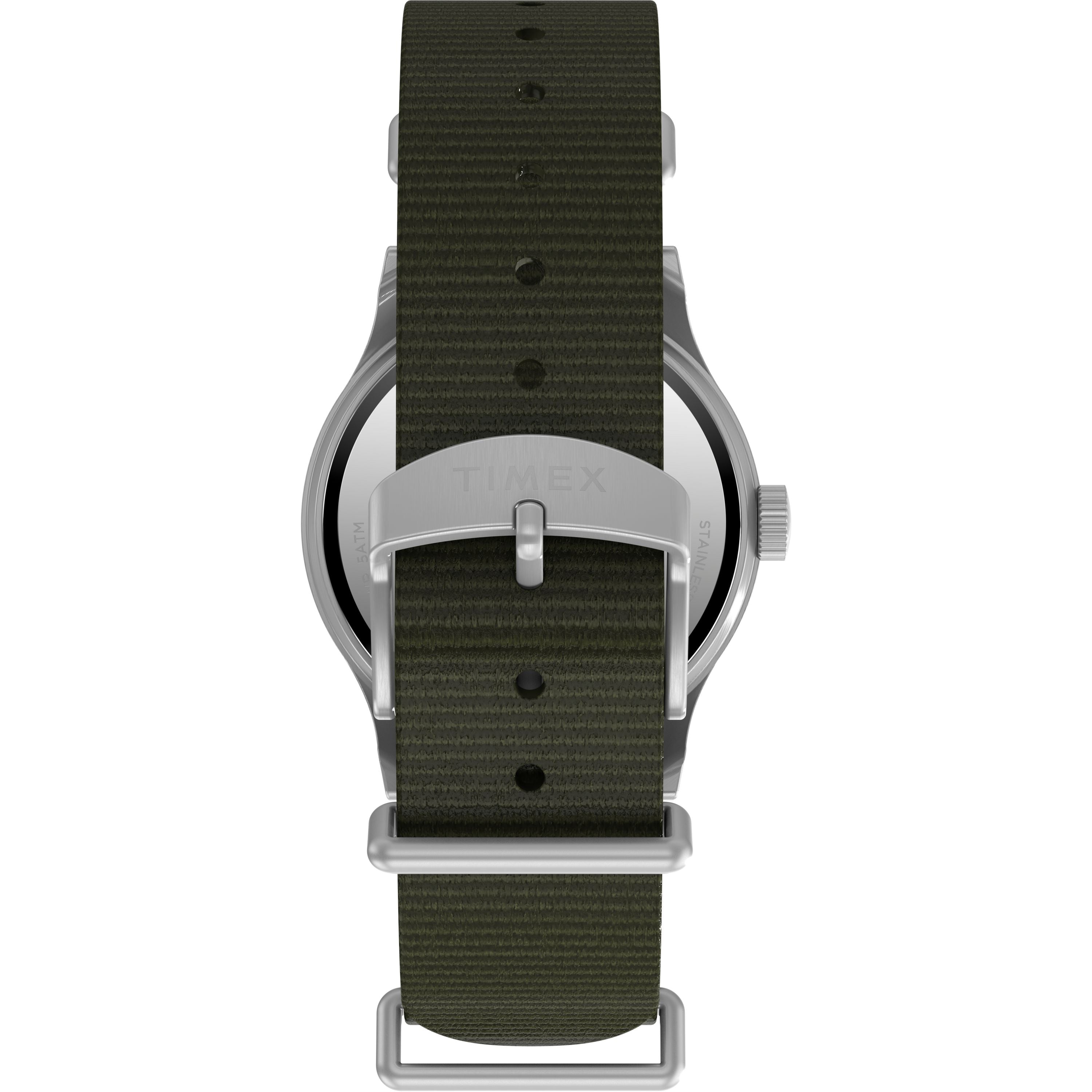A close-up of the Timex G SS MW SW MK1 36 BLK DL GRN STP 25 shows its military-style back, dark green recycled fabric strap, and silver buckle engraved with the Timex brand name.