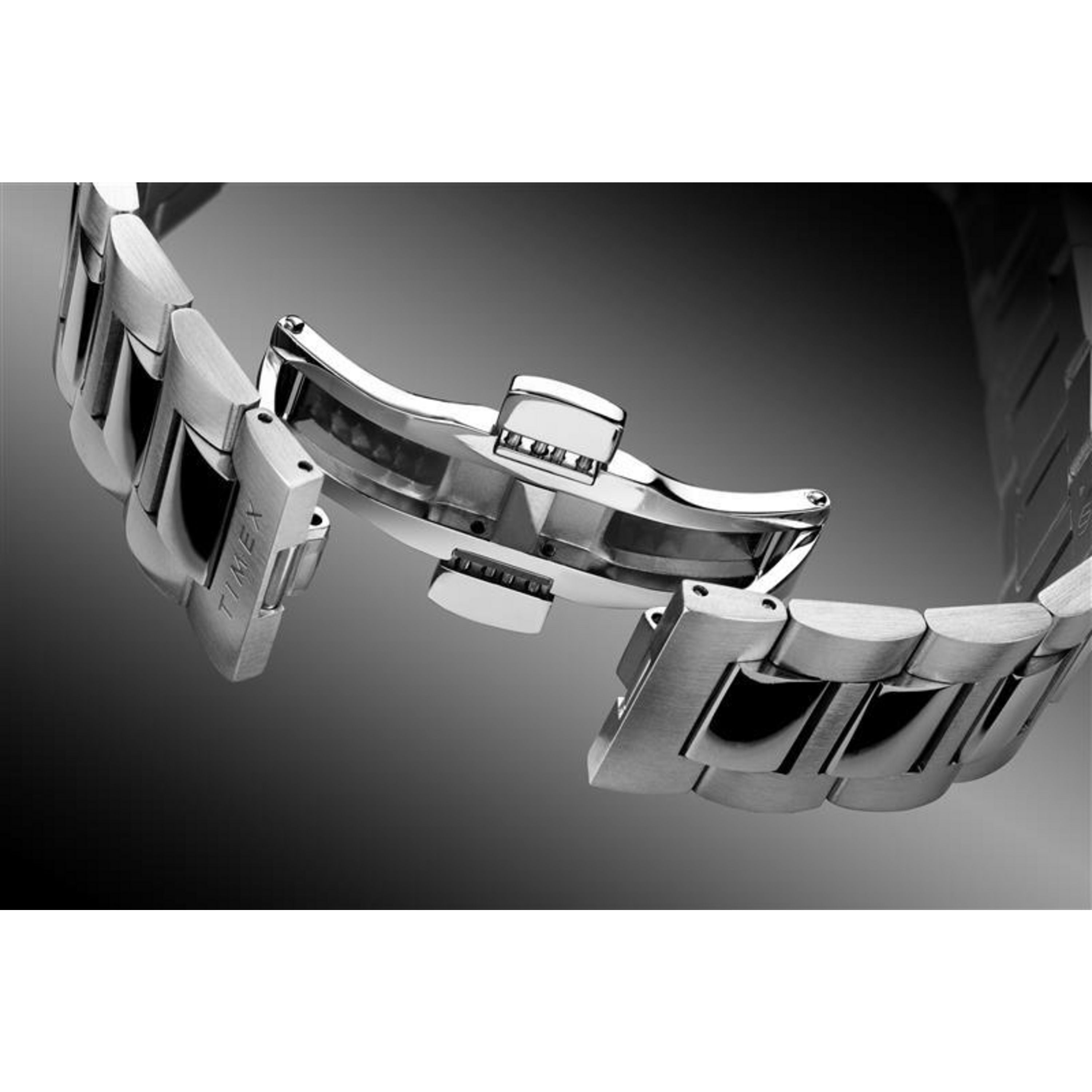 Close-up of the Timex Waterbury Heritage Chronograph’s stainless steel bracelet with an open deployment clasp, showing off the polished and brushed links against a gradient black and white background.