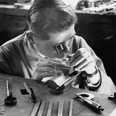 Person working with tools on a wooden surface in a workshop setting