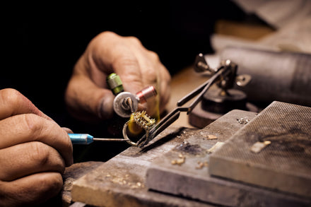 A close up of a welder's hands with a torch working on a ring 