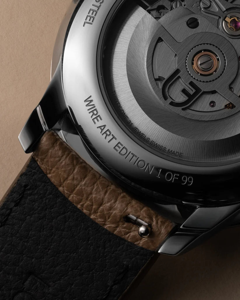 Close-up of a watch with a brown leather strap and visible brand name on a beige background