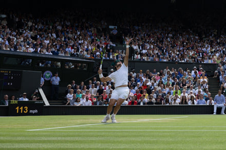 Tennis player serving on a grass court at Wimbledon with a crowd watching, serve speed 113 mph.