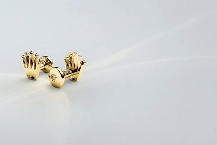 Rolex gold cufflinks on a white background