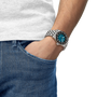 Person wearing a silver watch with a blue face on a white background